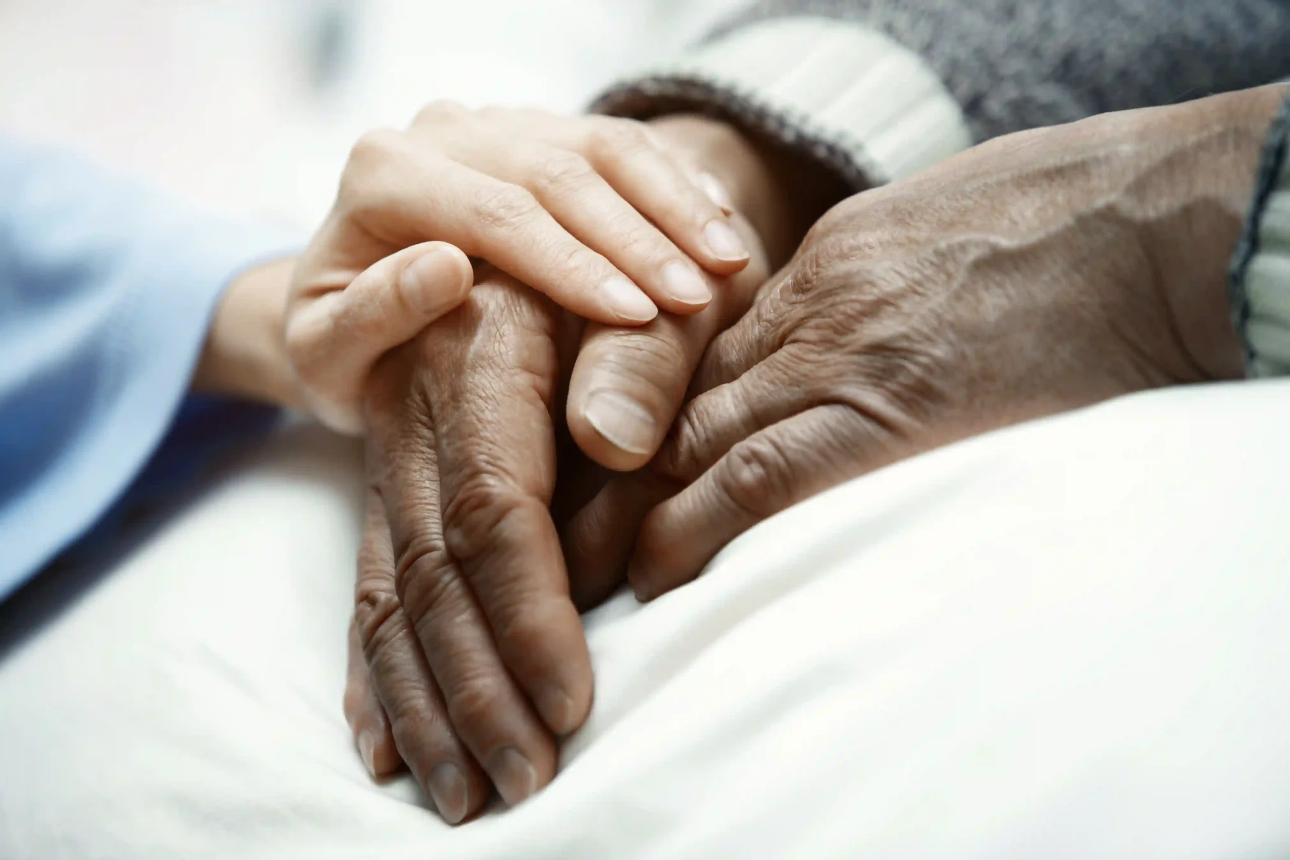 Une personne tient avec attention la main d’une personne âgée